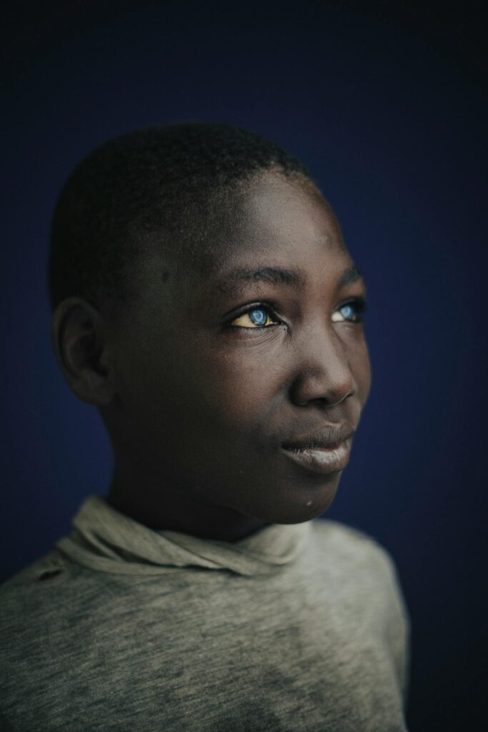 A thoughtful portrait of a young boy gazing upward with striking blue eyes.
