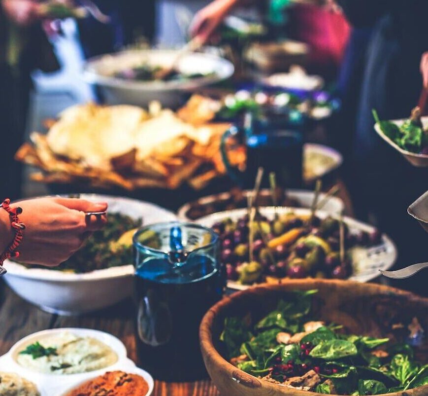 A vibrant buffet spread with salads, skewers, and dips at a lively indoor gathering.