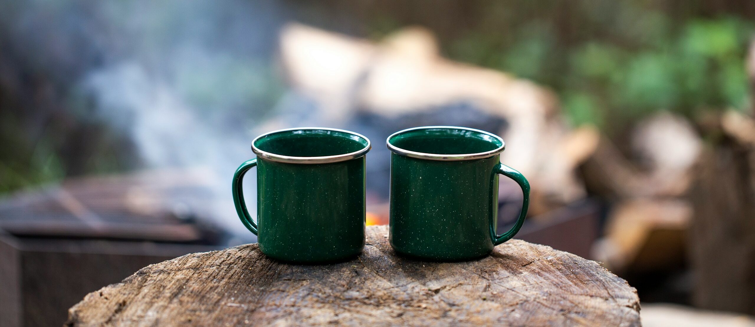2 green ceramic mugs on brown wooden log