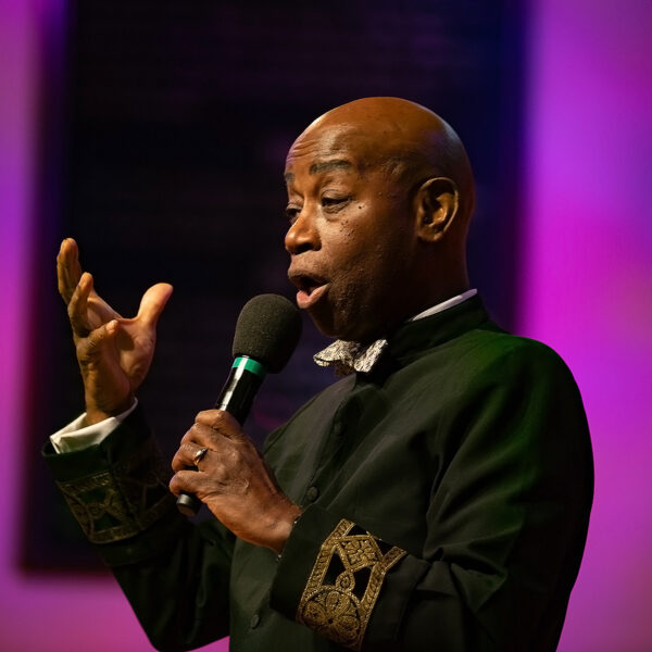 Black man holding a microphone, speaking