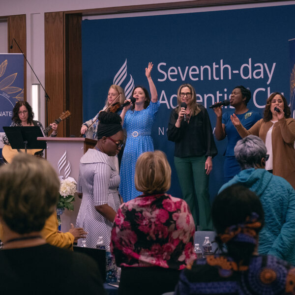 Praise team singing on a stage in front of a crowd.