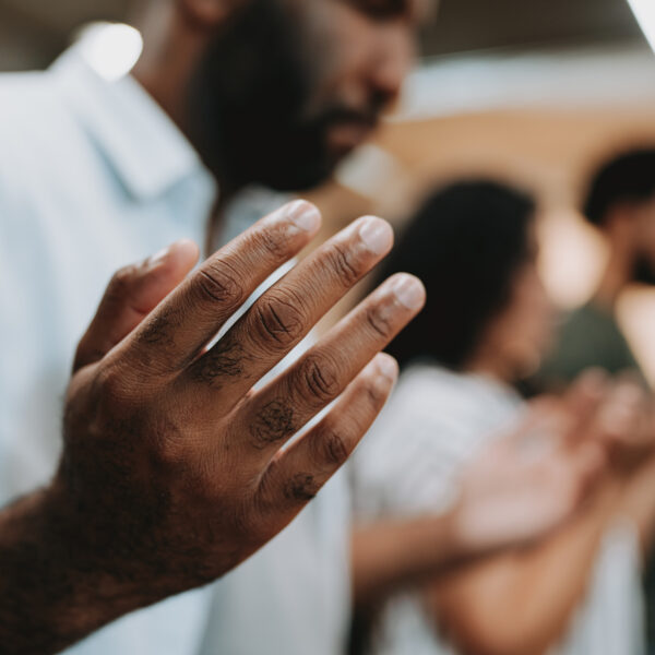 Photo of black man with group praying with open hands - Jacob Wackerhausen