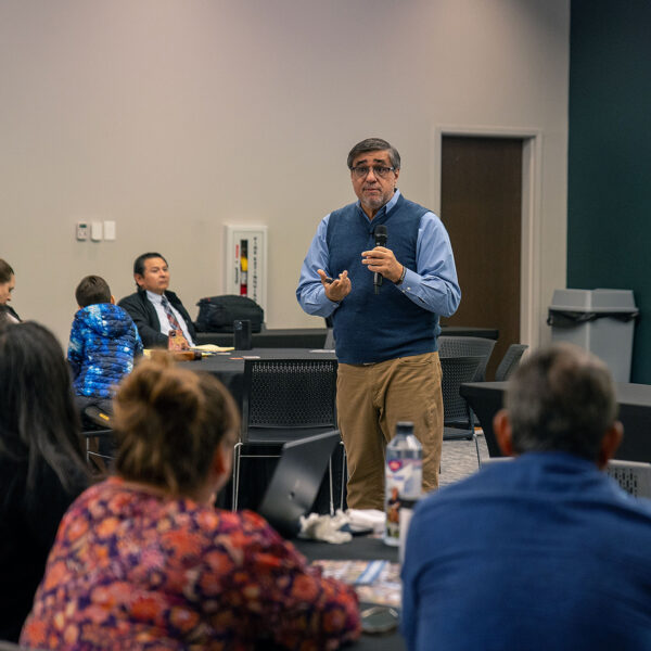 A Hispanic man speaks in front of a small crowd