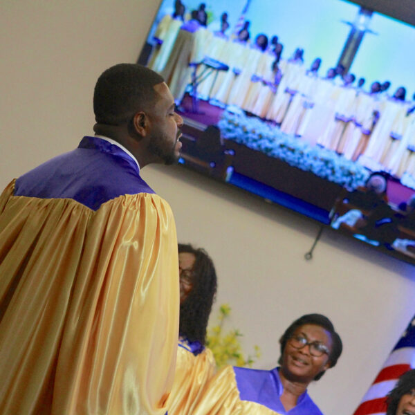 Close-up of Ghanaian choir in robes with image of full choir visible on a screen