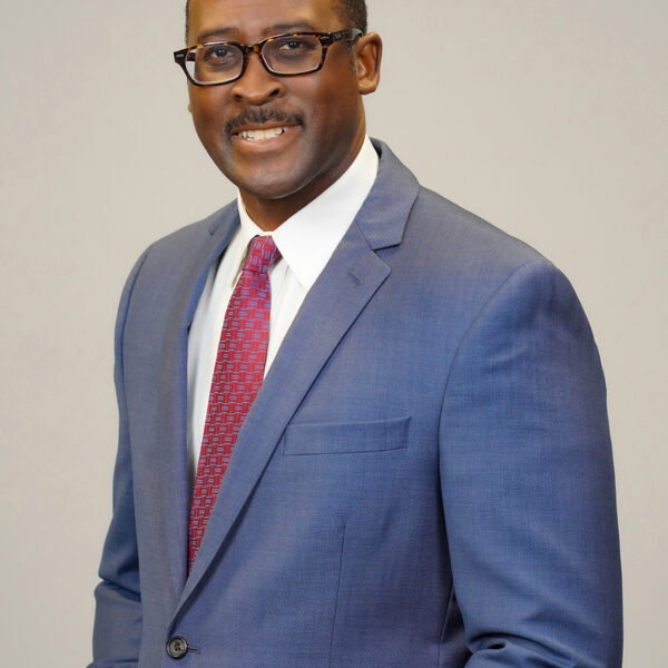 Headshot of a smiling black man in a suit