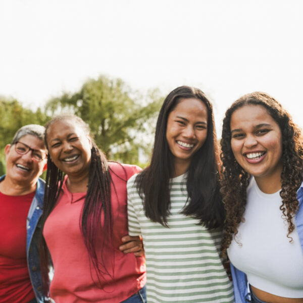 Multi generational women with arms around each other's shoulders together outdoors