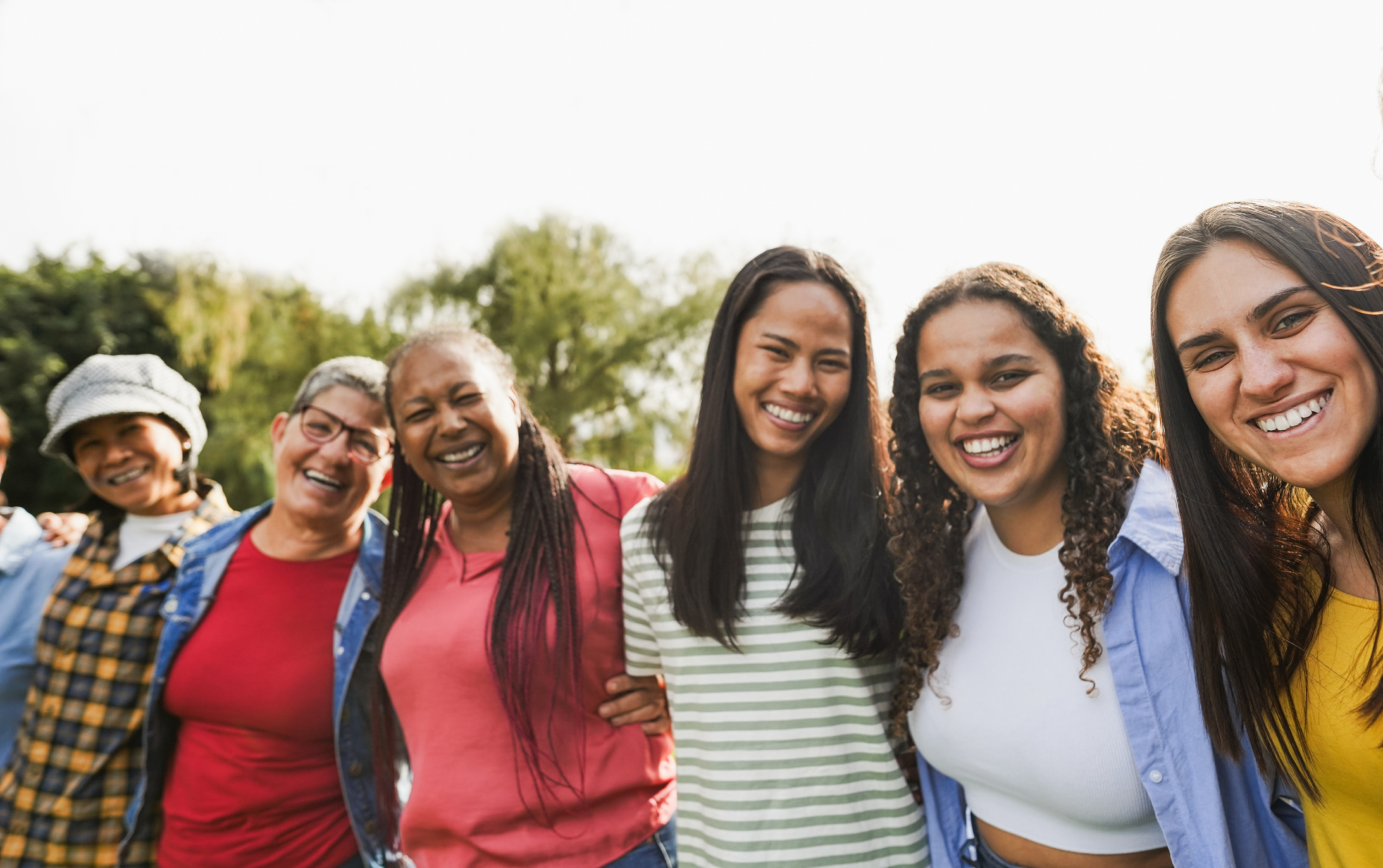 Multi generational women with arms around each other's shoulders together outdoors