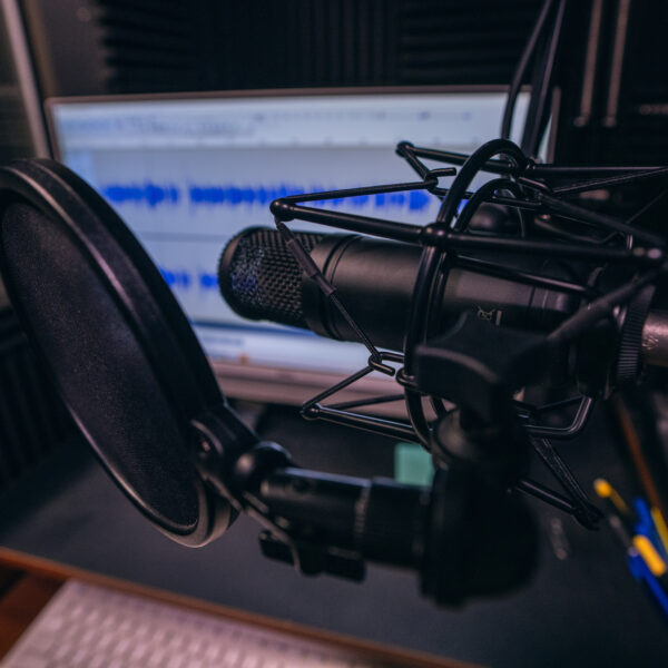 Close up of radio station microphone, mixer, computer, sound board