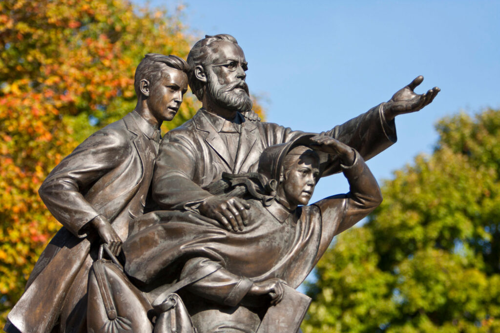 Photo of a bronze statute of a man and two children from the 1800s looking forward