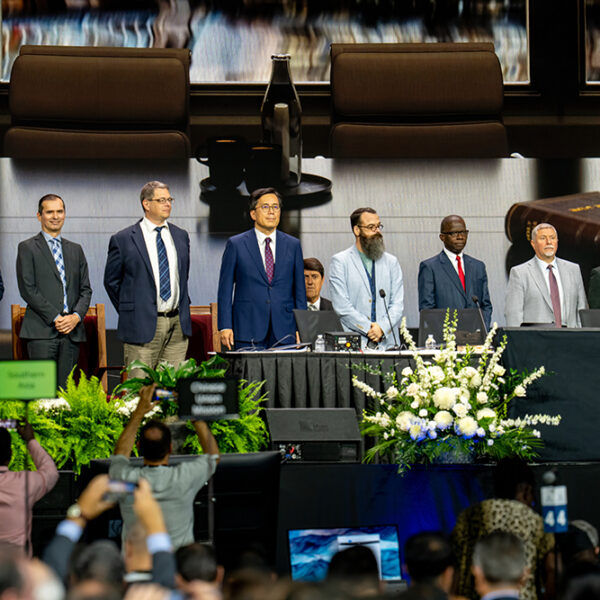 A diverse group of men in suits stand on a stage
