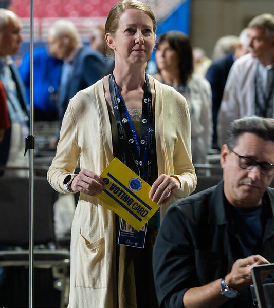 Liz Kirkland stands at the voting floor with her yellow voting card.