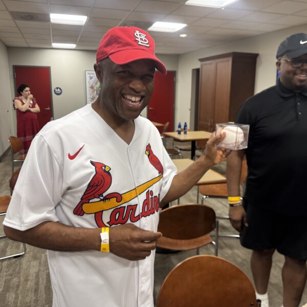 Middle age Black man in Cardinals shirt with baseball smiles