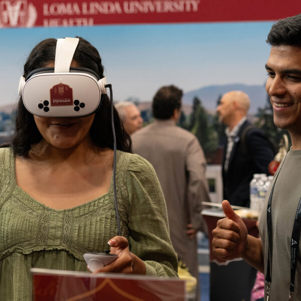 A young woman wears a VR headset as a young man looks on