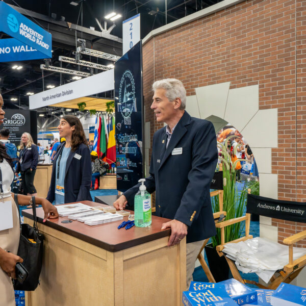 Reporter Herma Percy talks to a representative from Andrews University at the education exhibit.