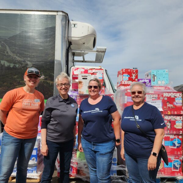 Volunteers stand in front of donations at distribution center.