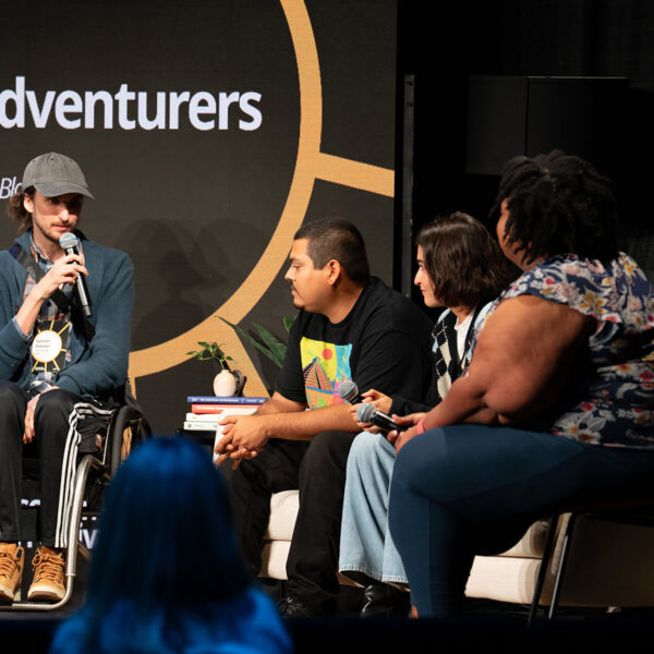 A man in a wheelchair speaks to three other people on Sonscreen stage.