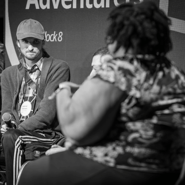 Young man in a wheelchair speaks to a woman on a stage