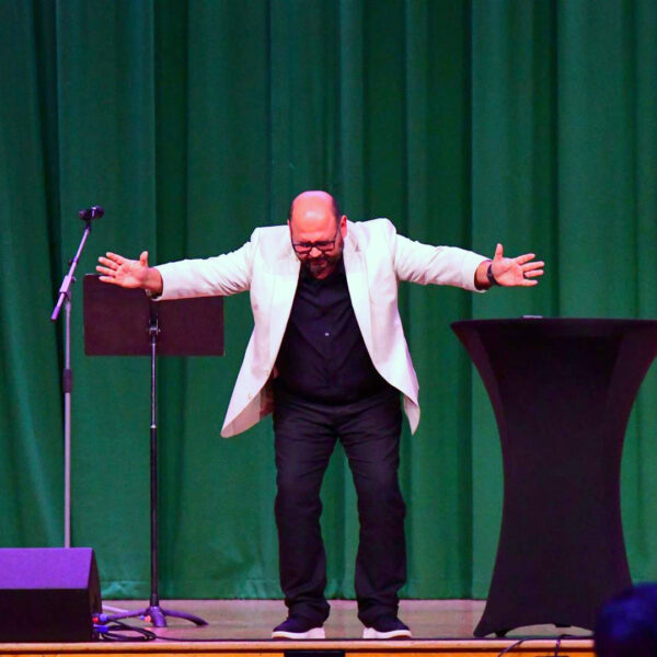 Robert Cornado, pastor of the Chattanooga Hispanic Community Seventh-day Adventist Church, spreads his arms in reverence on stage during prayer.