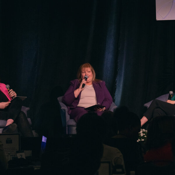 Three women sit together on a stage.