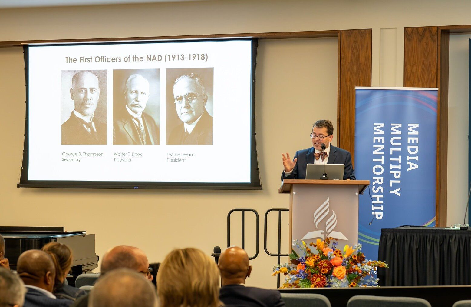 Man giving a powerpoint presentation to conference attendees.