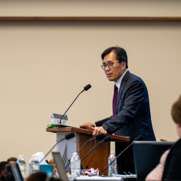 Middle age Asian man stands at a microphone during meetings at the North American Division auditorium.