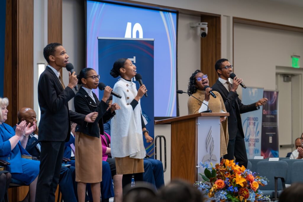 A small group of siblings sing on a stage.