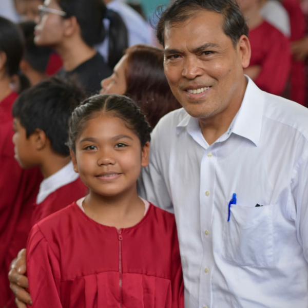 A young woman in a baptismal gown with a pastor.
