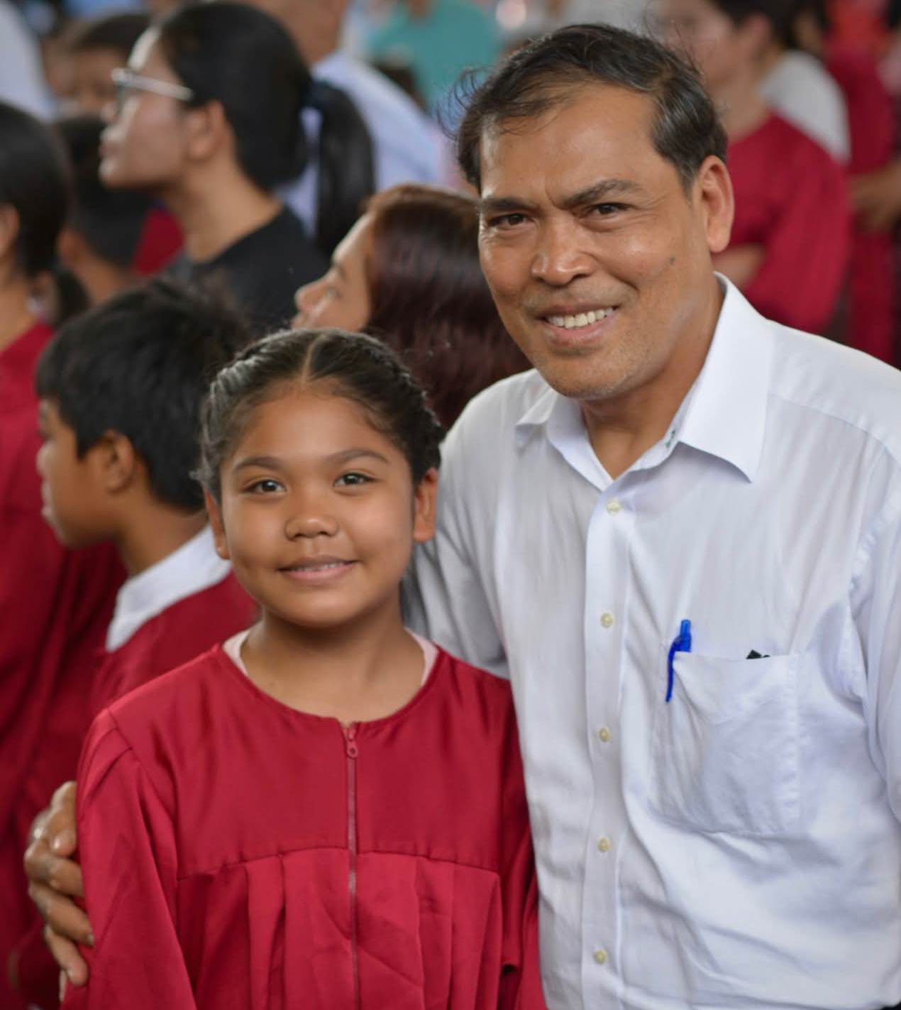A young woman in a baptismal gown with a pastor.