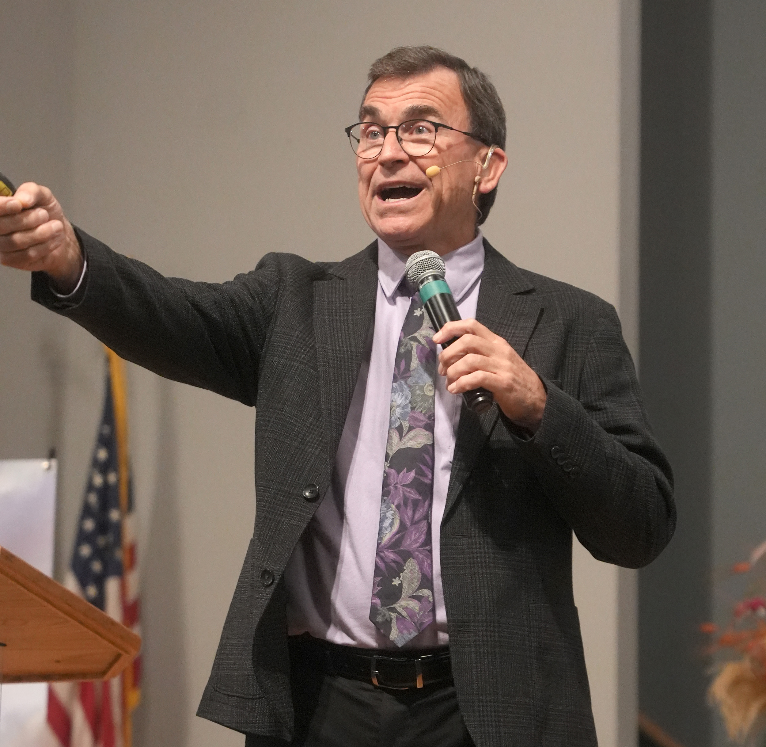 Man standing holding a microphone preaching to an audience.