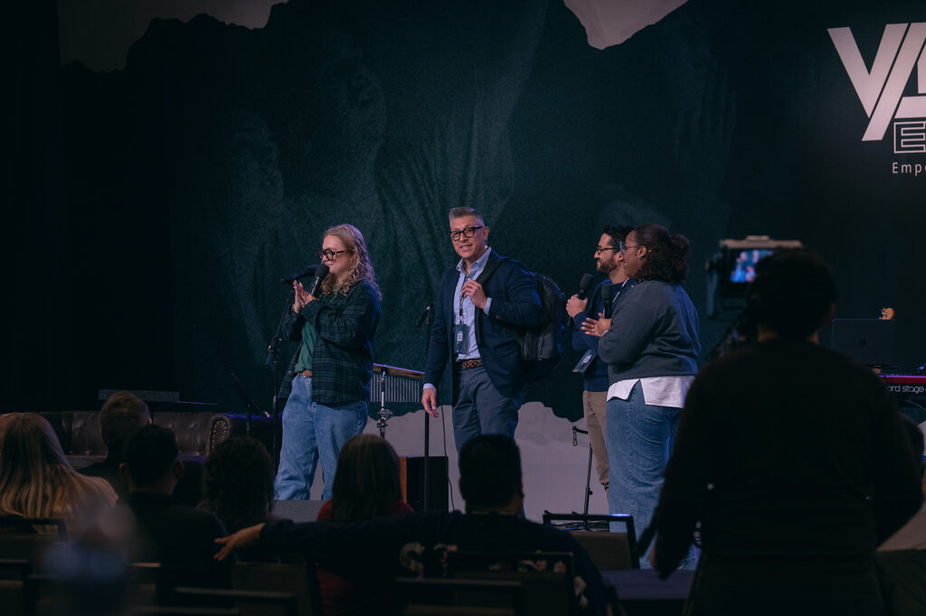 Four people holding microphones on a stage.