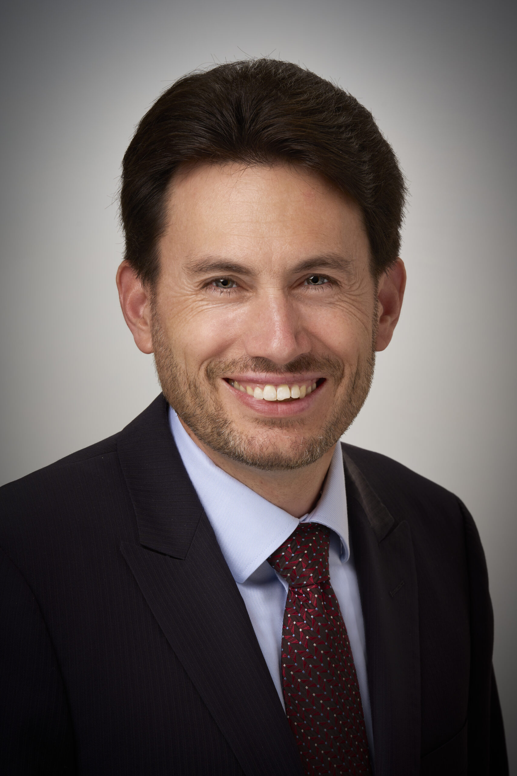 Caucasian man with dark hair wearing a suit and tie