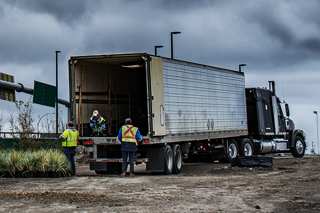 Image of three people in safety vests standing at the back of a freight truck, showcasing resilient logistics.