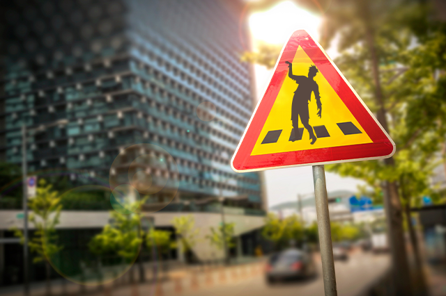 Image of a hilarious road sign featuring a zombie crossing the street.