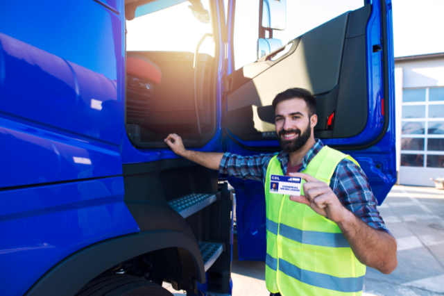 A man holding a CDL while standing in front of a blue truck