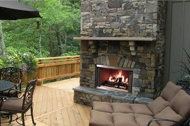 An outdoor stone fireplace on a wooden deck