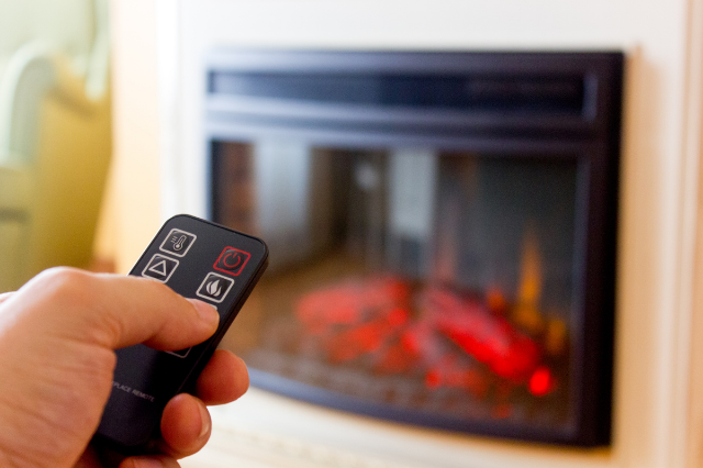 Close up of a person holding a remote for an electric fireplace