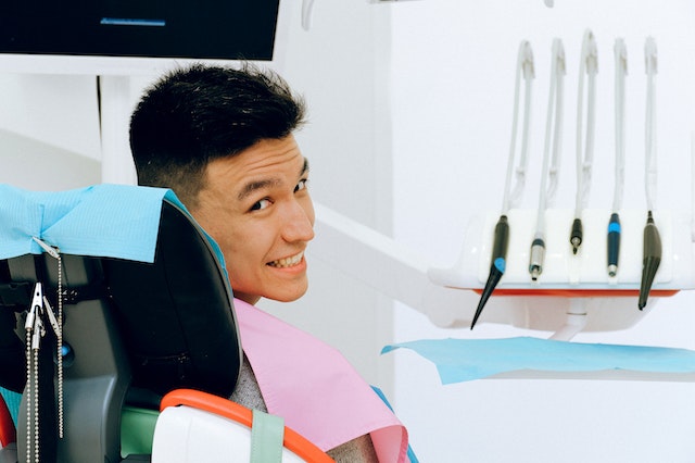 cheerful man is flashing a smile over his shoulder while seated in a dentist’s chair