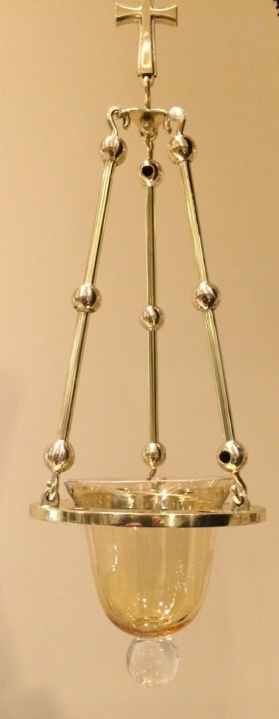 Brass lamp, by Aidan Hart, showing the play of light on the spheres and cross.